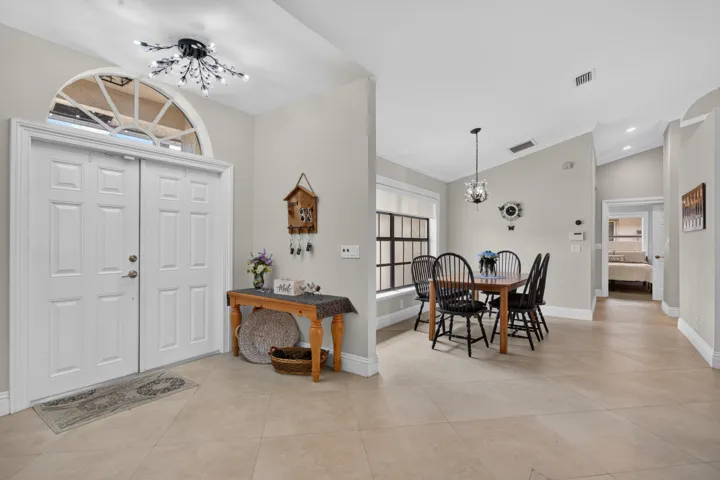 Double entry doors with an arched transom, tile flooring, vaulted ceilings, and crown molding