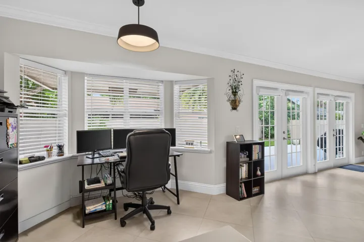 Recessed bay window with white blinds, crown molding, and light-toned tile flooring