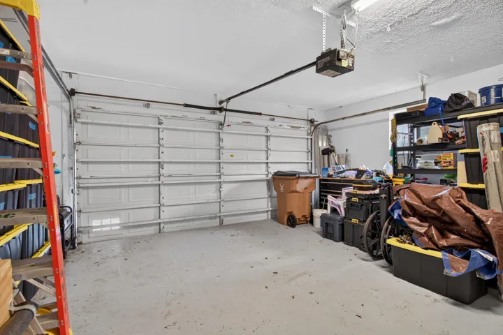 Garage with concrete flooring, overhead lighting, and an automatic garage door opener