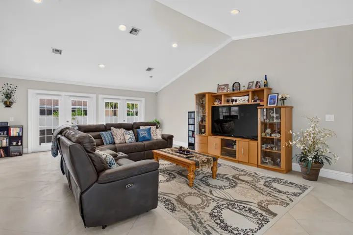 Vaulted ceiling with recessed lighting, light tile flooring, and multiple French doors