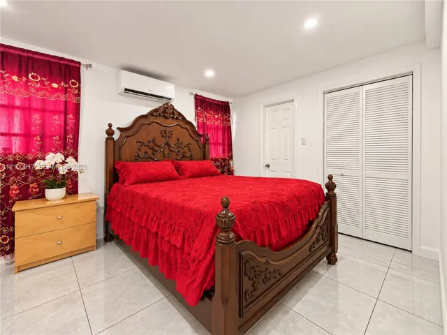 White walls with recessed lighting, split-unit air conditioning, and a louvered bi-fold closet door