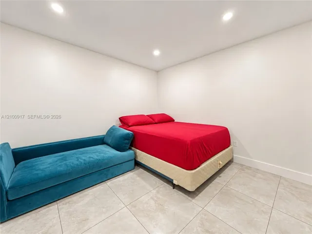 Recessed lighting illuminating a room with light-toned walls and large format floor tiles