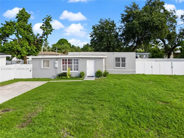 Single-story residence with a gray facade, white privacy fencing, and a concrete driveway