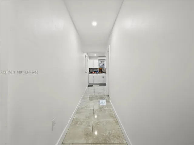 Recessed ceiling lighting illuminating a hallway with light-colored walls and tiled flooring