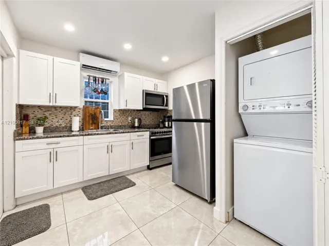 Kitchen featuring white cabinetry, stainless steel appliances, granite-style countertops, and a mosaic tile backsplash