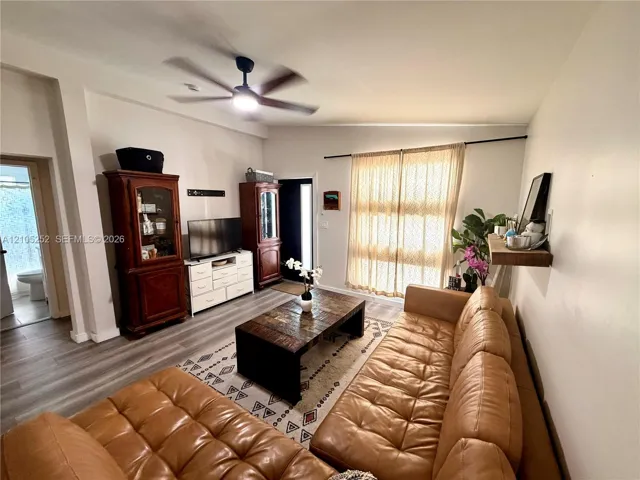 Expansive living area featuring a ceiling fan, wood-finish flooring, and natural light