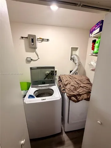 Dedicated laundry area with wood-finish flooring and built-in shelving