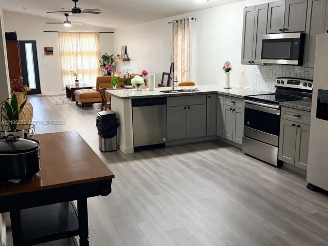 Kitchen featuring gray shaker-style cabinetry, stainless steel appliances, granite-style countertops, and a white subway tile backsplash