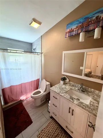 Vanity with integrated sink and marble-look countertop, white framed mirror, and rectangular floor tiles