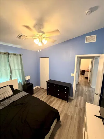 Vaulted ceiling with an attached ceiling fan, wood-finish flooring, and a built-in closet with bifold doors