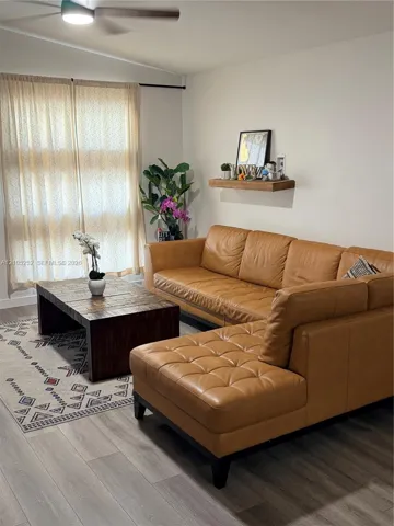 Wood-finish flooring, light-toned walls, and a ceiling fan with integrated lighting