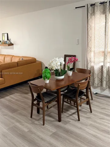 Wood-finish flooring throughout, light-toned walls, and a window with curtains