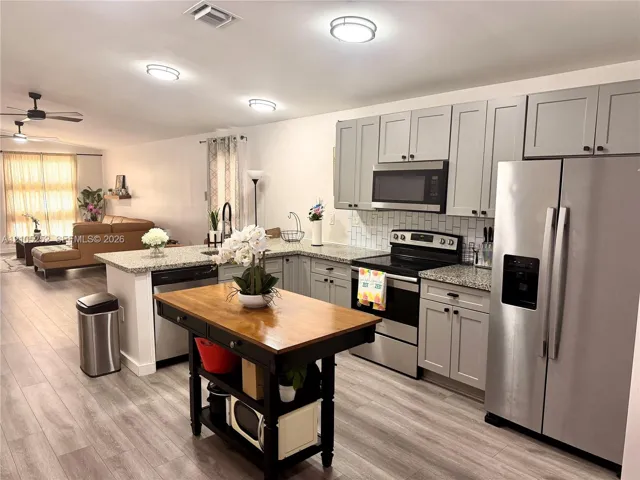 Kitchen featuring gray cabinetry, stainless steel appliances, and light-toned countertops