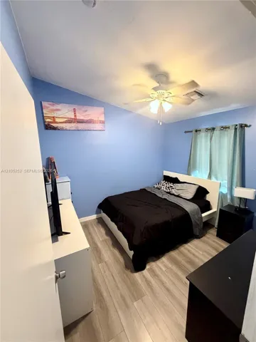 Wood-finish flooring, ceiling fan, and window with curtains