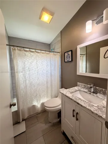 White vanity with double-door cabinetry, integrated sink, and stone-finish countertop
