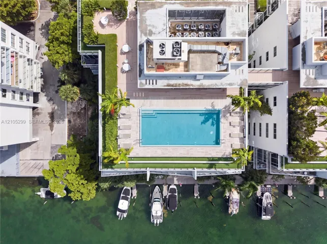 Waterfront property featuring a private swimming pool, multiple boat slips, expansive green spaces, and contemporary building exteriors