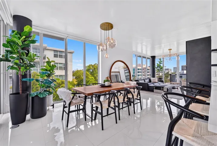 Expansive living space with white tile flooring, floor-to-ceiling windows, and a multi-light pendant fixture