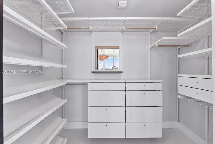 Integrated closet system with extensive shelving, built-in drawer units, hanging rods, and an overhead window