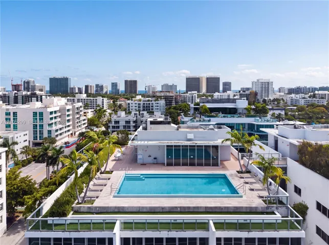 Rooftop swimming pool with surrounding deck space, integrated planters, and distant cityscape