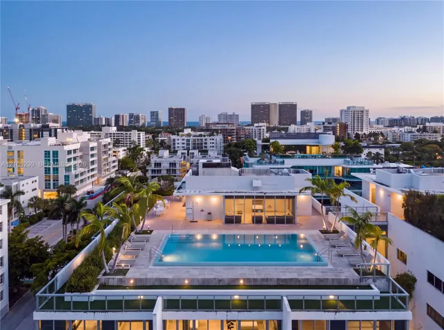 Rooftop pool with integrated lighting, surrounding paved patio, and perimeter landscaping