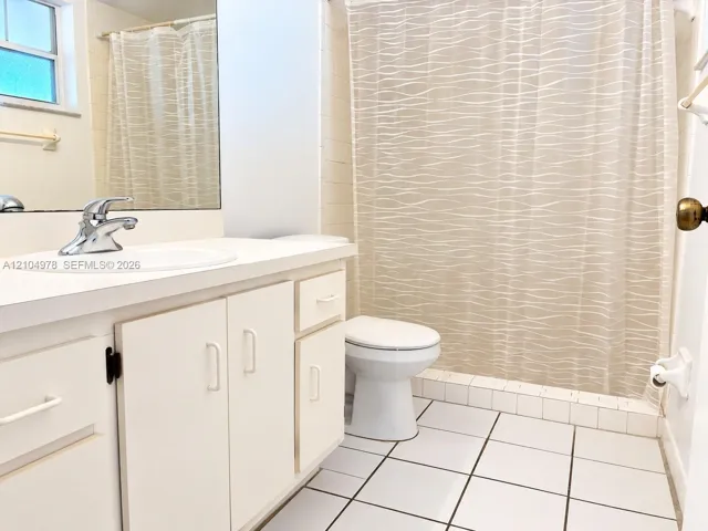 Bathroom featuring an integrated sink, vanity with storage, chrome faucet, wall-mounted mirror, and tiled flooring
