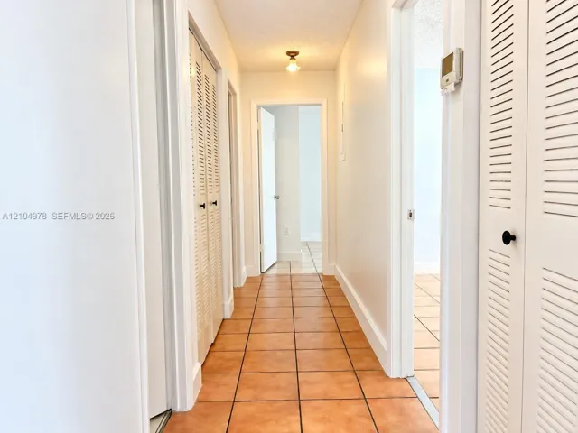 Hallway with terracotta-style tile flooring and white louvered bifold doors