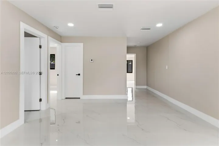 Recessed ceiling lighting, white interior doors, bright white flooring, and light-toned wall finishes