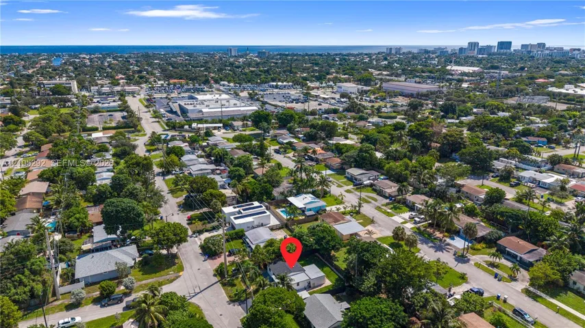 Aerial depiction of a residential neighborhood with a distant urban skyline and ocean