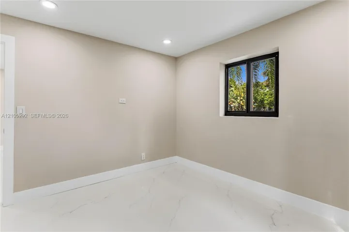 Recessed lighting, light neutral wall paint, white trim, white marble-look flooring, and a black-framed window