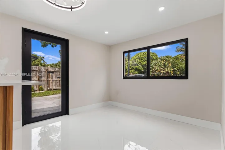Recessed lighting, wood-finish cabinetry, bright white flooring, black-framed glass door, and black-framed window
