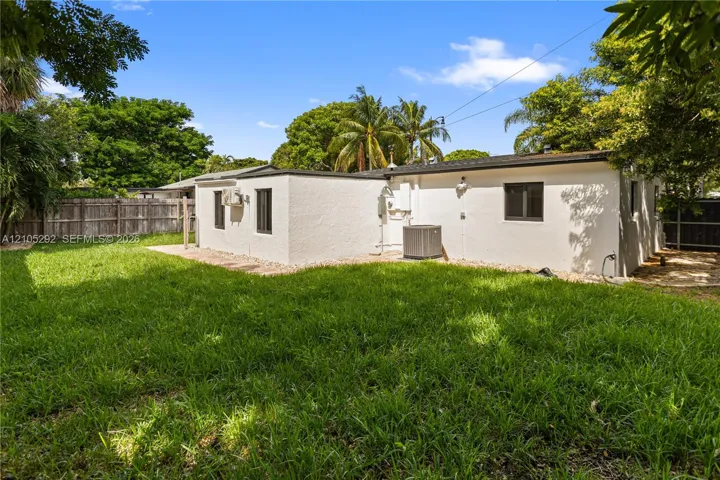 Expansive backyard with a manicured lawn, established privacy fencing, and mature trees