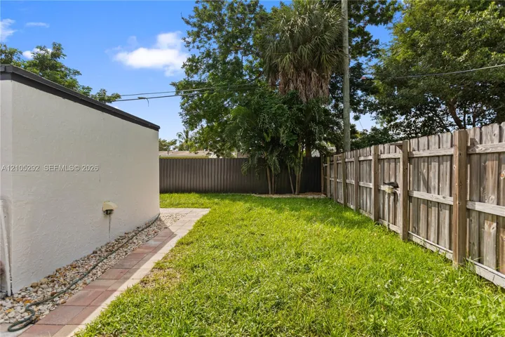 Expansive grassy yard with wood-plank fencing, paver pathway, and mature trees