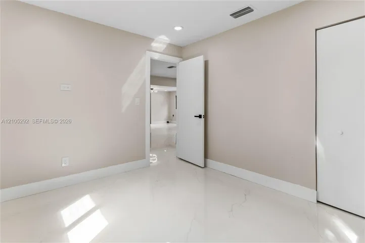 Polished light-toned flooring, neutral wall tones, recessed lighting, and a white door with dark hardware