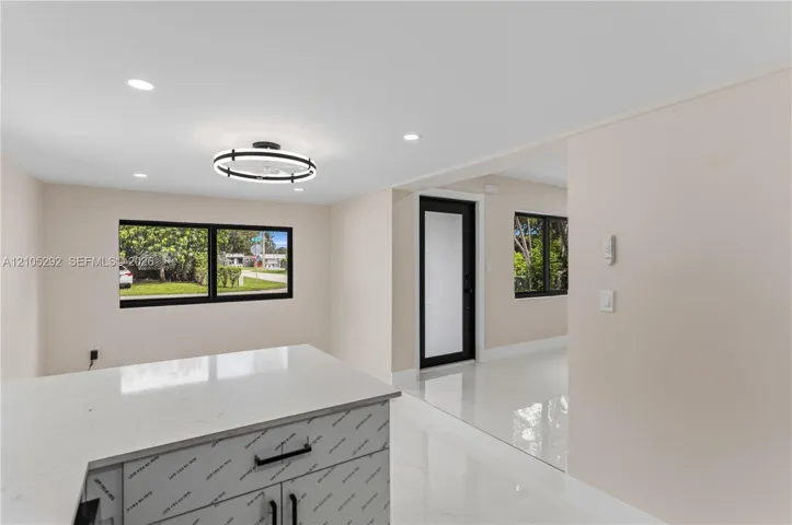 Sleek kitchen island with a light-colored countertop and dark hardware, complemented by recessed lighting and a modern circular light fixture