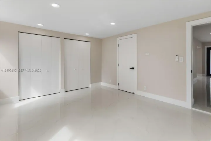 Recessed lighting, light-toned walls, and white tile flooring