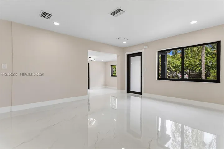 Polished tile flooring, recessed ceiling lighting, light-toned walls, and black-framed windows