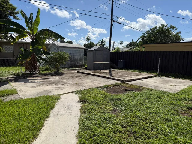 Spacious backyard with concrete patio areas, two storage sheds, and a wooden privacy fence