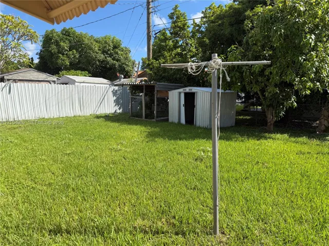 Expansive yard featuring a metal storage shed, mature trees, and a privacy fence