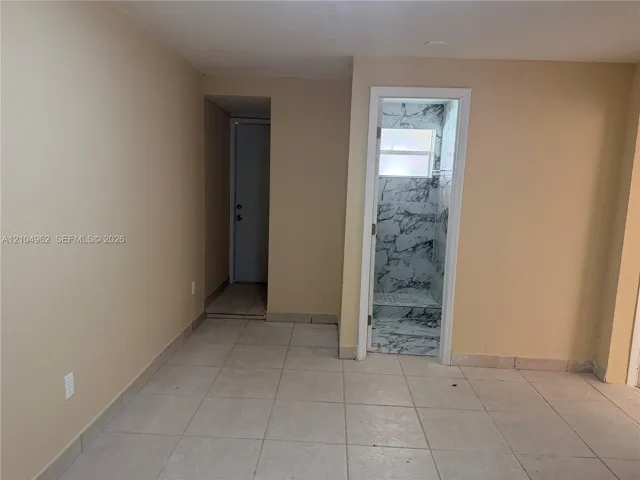 Tiled flooring throughout, neutral wall finishes, and a contemporary shower enclosure with marble-patterned wall panels