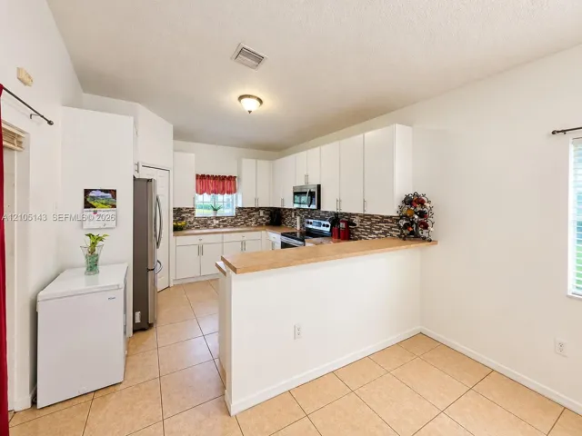 Kitchen featuring white cabinetry, stainless steel appliances, a tiled backsplash, and a breakfast bar