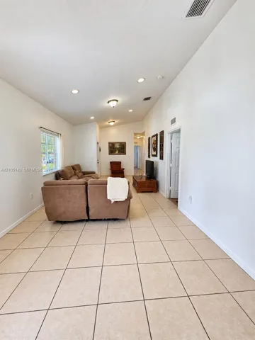 Spacious living area featuring large format tile flooring, recessed lighting, vaulted ceilings, and natural light from a window