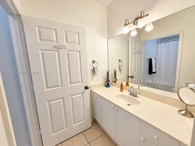 Vanity with integrated sink, extensive countertop space, white cabinetry, and a framed mirror