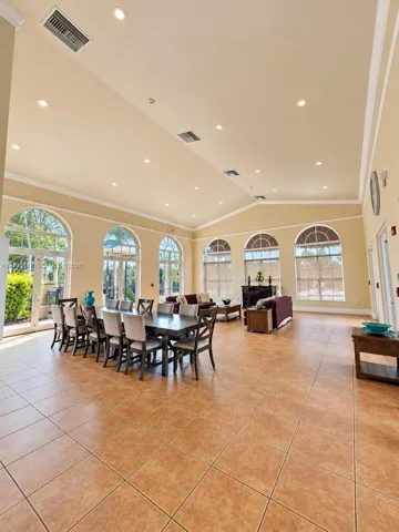 Spacious common area featuring large format tile flooring, vaulted ceilings, recessed lighting, and multiple arched windows