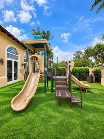Outdoor play structure with two slides and stairs, set on a green artificial turf surface