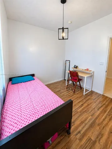 Wood-finish flooring with a modern pendant light fixture and white walls