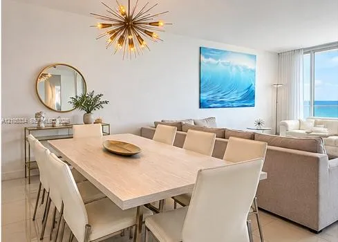 Spacious dining area with a modern sputnik chandelier, light wood-finish dining table, and tile flooring