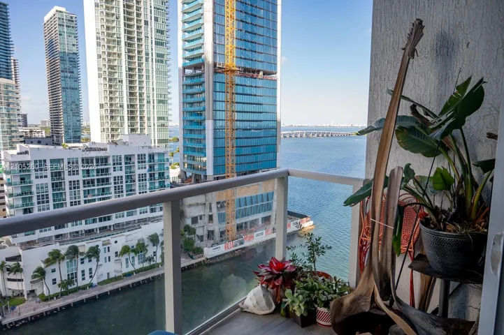 Balcony with a glass railing, offering a waterfront perspective of the distant bridge