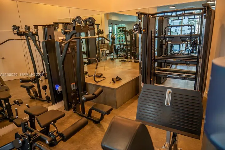 Dedicated fitness area featuring extensive mirrored walls, multiple exercise machines, and a raised platform