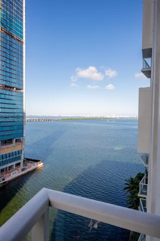 Expansive water scenery with distant land, visible from a balcony with a white railing