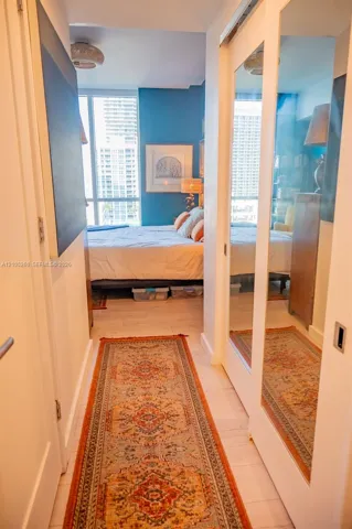 Light wood-finish flooring, sliding mirrored closet doors, recessed ceiling light, and full-height windows